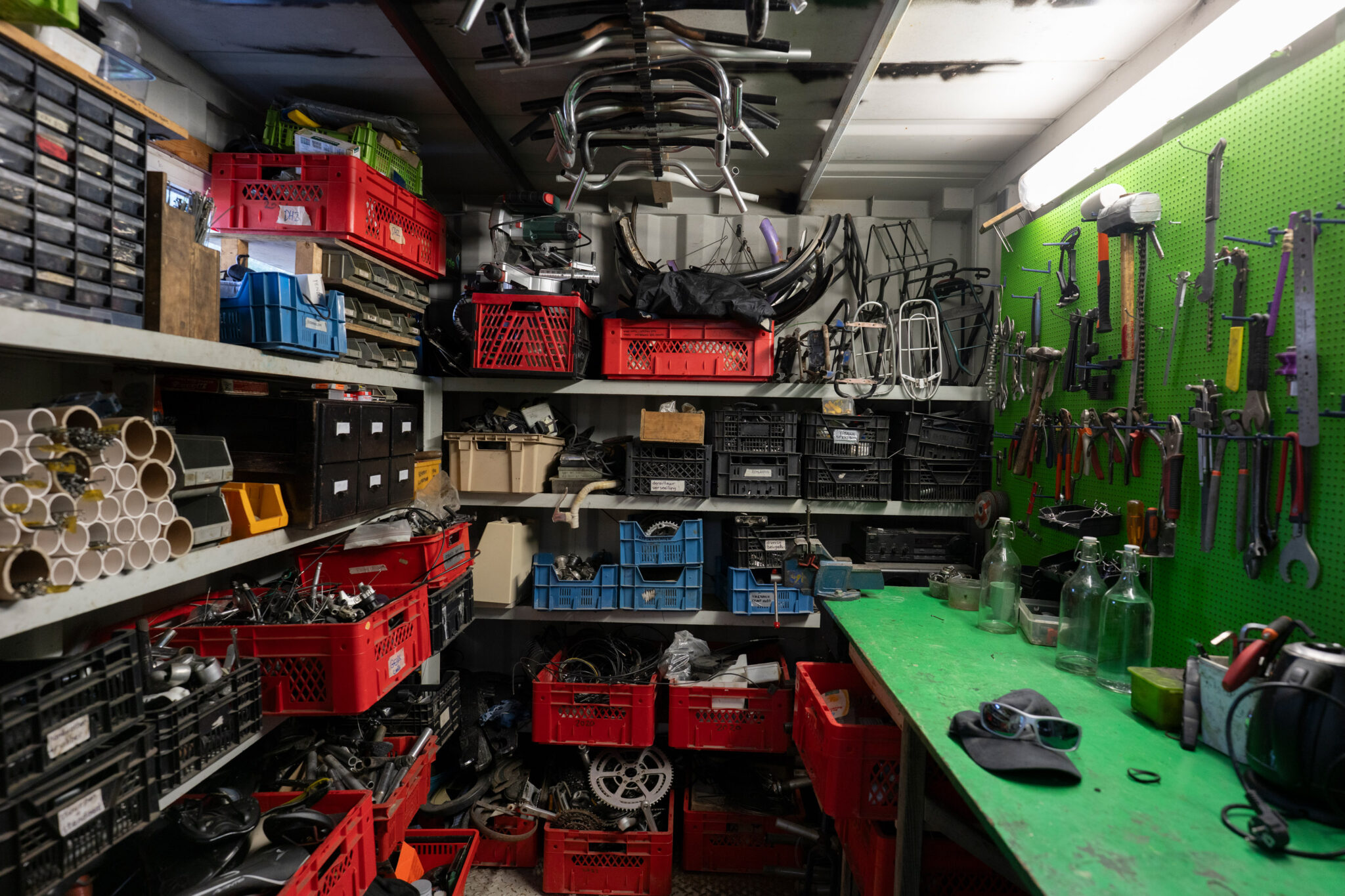 A photo of the workshop within the container, with the workbench on the right and the other walls containing boxes of bike parts and tools
